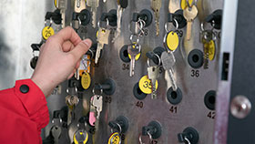 Nahaufnahme: Eine Hand nimmt einen von vielen Schlüsseln von einem Schlüsselsafe.