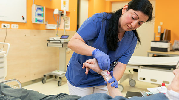 Im Behandlungsraum: Senay C. legt eine Kanüle in den Arm eines Patienten.