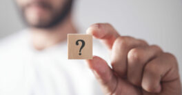 Man Showing Question Mark On Wooden Cube.
