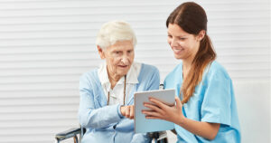 Seniorin mit Pflegekraft und Tablet